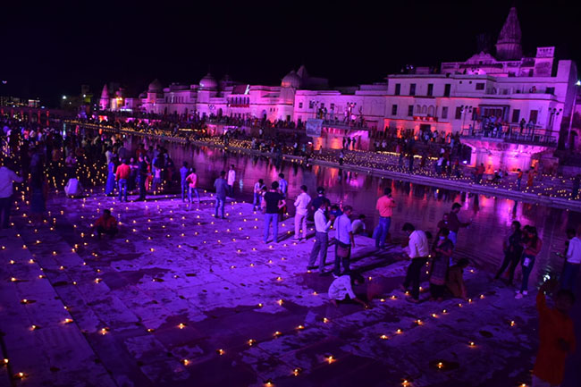 अयोध्या में राम की पैड़ी पर राम मंदिर भूमि पूजा का उत्सव मनाते सैकड़ों लोग दिखाई दे रहे