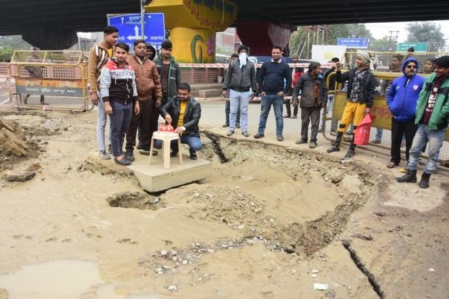 गड्ढे को न भरने पर केक काटकर किया प्रदर्शन