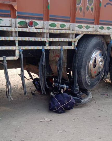 ट्रक के नीचे आया बाइक, बाल-बाल बचा पुरा परिवार