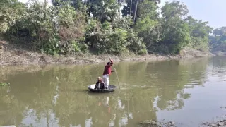 लोहे की कड़ाही में बैठकर नदी पार करते ग्रामीण