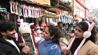 बच्चे को टाय कैप पहनाकर दिखाते माता-पिता
