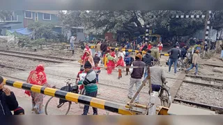 बंद रेलवे फाटक के नीचे से निकलते लोग