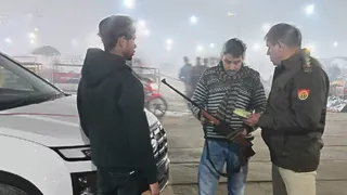 प्रयागराज माघ मेला क्षेत्र में कार सवार शस्त्र लिए युवक के कागजात चेक करते पुलिसकर्मी।