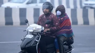 दिल्ली में ठंड के बीच स्कूटी से जाते लोग। जागरण