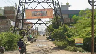 कॉलोनी में हाईटेंशन लाइन टॉवर के नीचे से गुजर रहे वाहन।