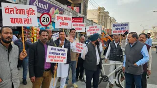 टोल बढ़ाने के खिलाफ प्रदर्शन करते हुए लोग।