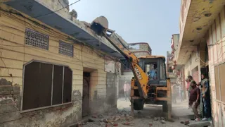 घर गिराते हुए बुलडोजर।