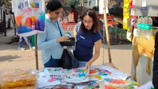 सेक्टर 27 स्थित इंदिरा मार्केट में होली के लिए सजी दुकान में खरीदारी करतीं महिलाएं। जागरण