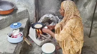 चूल्हे पर खाना पकाते हुए महिला।