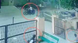 महिला से लूटपाट करते अपराधी को देखते दो शख्स। वीडियो ग्रैब