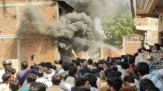 प्रयागराज के कोरांव में हार्डवेयर गोदाम में आग लगने के बाद उठता धुआं, जुटी भीड़। जागरण