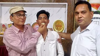छात्र शिवा को मिठाई खिलाकर शुभकामनाएं देते प्रधानाचार्य संजय कुमार मिश्रा। जागरण