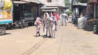 धूप से बचते हुए घर जाते बच्चे।