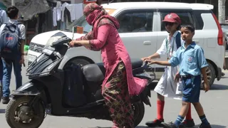 गर्मी में स्कूटी खराब होने पर बच्चे के जाती महिला। जागरण