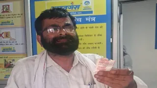 सरधना में भारत गैस एजेंसी पर हंगामे के दौरान हाथ में सल्फास की गोली का पैकेट लिए हुए शिक्षक। जागरण