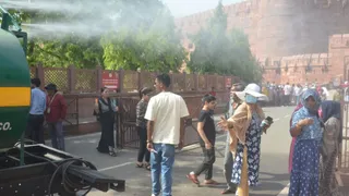 दोपहर में फुहारों के बीच पर्यटक।