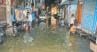 माया बाजार में जलभराव के बीच से गुजरते लोग l जागरण