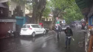 बारिश के बीच गुजरते लोग।