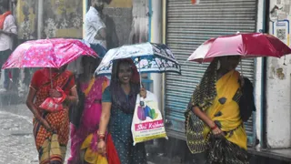 मुरादाबाद। जिगर कालोनी से तेज वर्षा में छाता लेकर गुजरती महिलाएं।