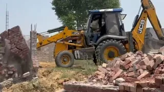 अवैध जमीन पर बना मकान गिराते हुए बुल्डोजर।