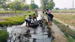 जल भराव के कारण फिसल कर गिरे बाइक सवार को उठाते युवक। जागरण