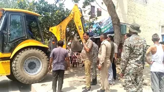 साधु की कुटिया ध्वस्त करता बुलडोजर।