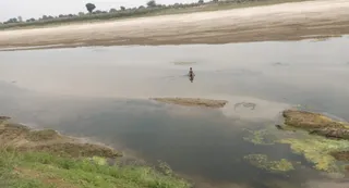 ग्राम नगवां के समीप राप्ती नदी को चल कर पार करता बच्चा। जागरण
