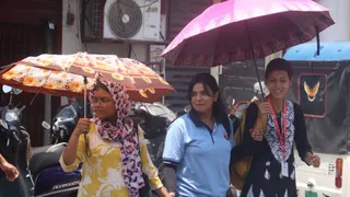 घंटाघर के पास गर्मी से बचने के लिए छाता लेकर जाती युवती।जागरण