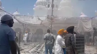 शहीदां साहिब गुरुद्वारे में टेंट से उठता धुआं व आग पर काबू पाते हुए श्रद्धालु व सेवादार।
