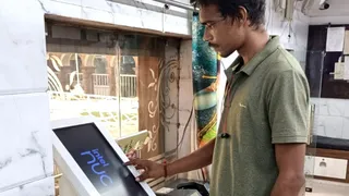 मंदिर कार्यालय में आई मशीन को ऑपरेट कर दिखाता कर्मचारी।