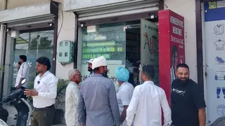 दुकान का क्षतिग्रस्त शीशा व एकत्रित भीड़।