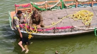 मानसी गंगा में डूबे बच्चे को निकालते गोताखोर।
