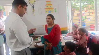 आगरा के परिषदीय स्कूल में पढ़ाई के बारे में शिक्षिका से पूछताछ करते डीएम मनीष बंसल।