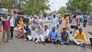 सड़क पर बैठ प्रदर्शन करते हुए परिजन।