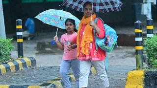 रविवार को हो रिमझिम वर्षा में गोल डाकखाना के समीप छाता लेकर जाती बच्ची और महिला। जागरण