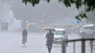 मंगलवार को बहादुर शाह जफर मार्ग पर हो रही वर्षा में छाता लेकर जाता राहगीर। जागरण