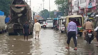 प्रयागराज में गुरुवार को झमाझम बारिश से सड़क पर जलभराव के बीच जाते वाहन व राहगीर। जागरण