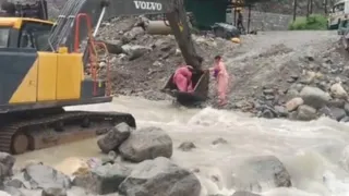 सौंग नदी का जलस्तर बढ़ने के बाद महिलाओं को पोकलैंड से नदी पार कराता आपरेटर। वीडियो ग्रैब