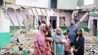वर्षा के दौरान गिरे मकान के बाहर खड़ा गुलफाम का परिवार