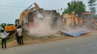 अधिग्रहित जमीन पर बने मकान को तोड़ता जेसीबी। जागरण