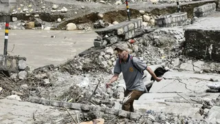 वर्षा के चलते टोंस नदी में आए तेज पानी के बहाव से क्षतिग्रस्त हुआ अस्थाई पुल से निकलता युवक। जागरण