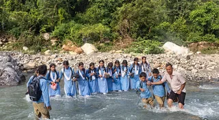 सौंग घाटी क्षेत्र में मानव श्रंखला बनाकर सौंग नदी को पार करते राइंका रगड़गांव के स्कूली बच्चे व पीठ पर बैठाकर बच्चों को नदी पार कराता ग्रामीण। सुधि पाठक
