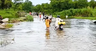 रोहुआ नाला में भरे पानी के बीच में होकर आते- जाते दियारा के लोग। जागरण