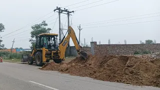 महम रोड के साथ भूमिगत लाइन बिछाने के लिए खोदाई करते हुए मशीन। जागरण