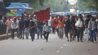 जनपथ रोड पर प्लास्टिक के बैरिकेड को पुलिस की ओर फेंकते प्रदर्शनकारी। जागरण
