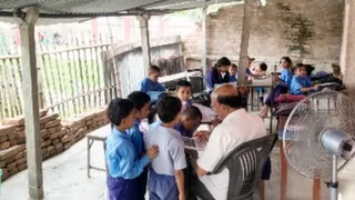 स्कूल के बरामदे में पढ़ाई करते बच्चे।