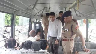 हाथरस में स्कूल बस में सफर के दौरान बच्चों से संवाद करते डीएम और एसएसपी।