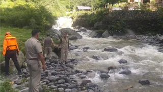 मनाली में नाले में बहे पर्यटक की तलाश में लगे पुलिस व एनडीआरएफ जवान। जागरण