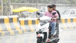 बारिश के बीच से निकलते स्कूटी सवार। जागरण