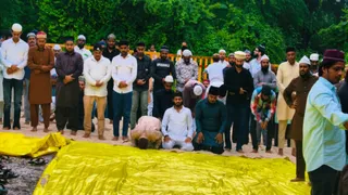 बारिश से गीली जमीन पर तिरपाल बिछाकर पढ़ी गई नमाज। (फोटो- जागरण)